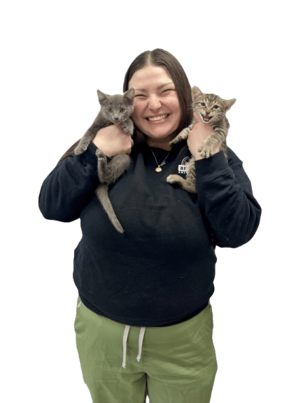 Woman smiling and holding two kittens, one gray and one tabby, against a plain white background.